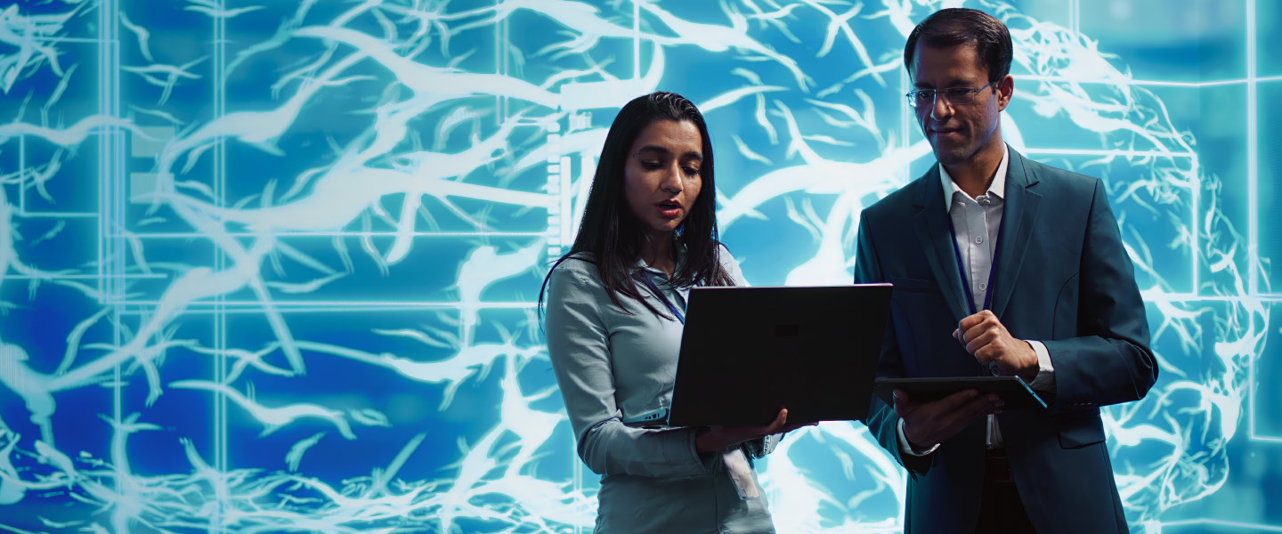 Mulher e homem na frente de um painel com notebook