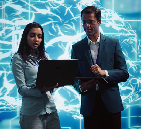 Mulher e homem na frente de um painel com notebook