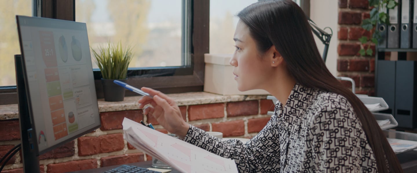 Mulher asiática comparando gráficos em papéis e computador, trabalhando para planejar o projeto de negócios no escritório de inicialização. Funcionário da empresa analisando documentos para projetar dados financeiros e estratégia.