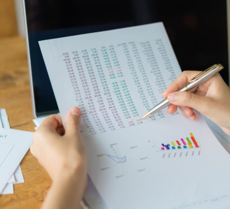 Mulher de negócios com gráficos financeiros e laptop na mesa.